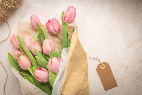 Pink tulip flowers bouquet on pale beige background. Flat lay, top view. Spring floral concept. - Fotó, kép