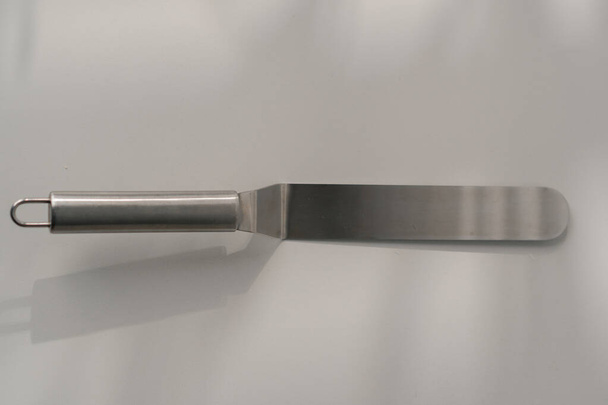 pečivo špachtle paleta nůž kuchyňské nádobí pro dorty na stole na bílém pozadí close-up - Fotografie, Obrázek