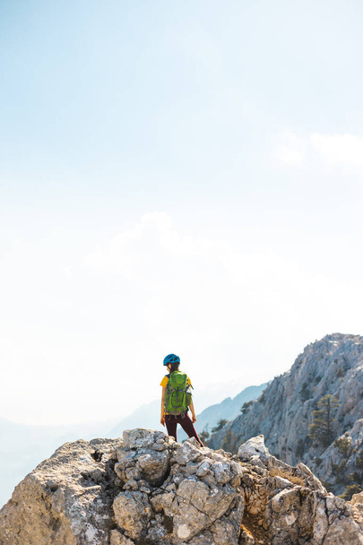 climber stands on top of the mountain. girl climber in a helmet and with a backpack mountains. the concept of adventure and hiking in the mountains. Turkey. - Photo, Image