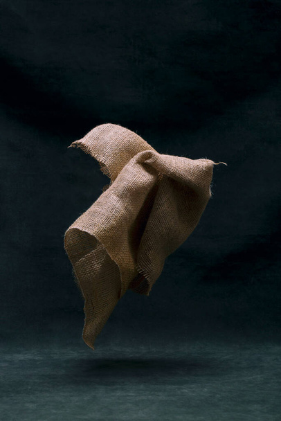 A piece of burlap in the air on a dark background - Фото, зображення