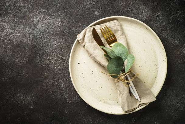 Table setting at black background. White craft plate, cutlery and decor. Top view image. - Valokuva, kuva