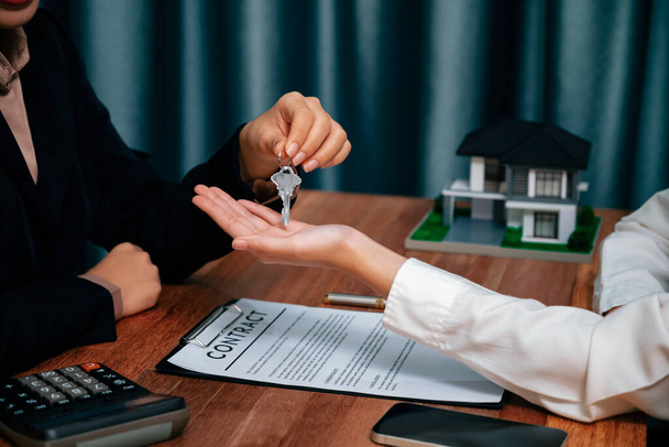 Агент по недвижимости передает ключ покупателю как символ владения после успешного завершения договора займа, воплощая в жизнь мечту о новом доме. Энтузиазм - Фото, изображение