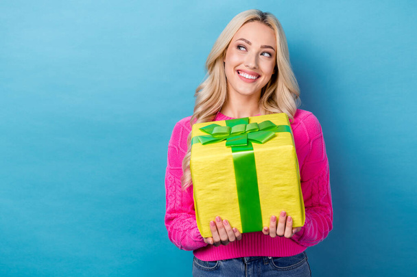 Photo of pretty gorgeous girl with wavy hairdo dressed pink sweater hold gift box look empty space isolated on blue color background. - Φωτογραφία, εικόνα