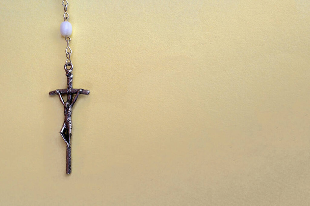 La cruz sobre un rosario sobre un fondo amarillo. Con espacio para texto. - Foto, imagen