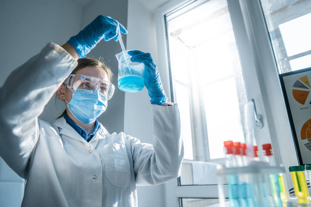 Η φωτογραφία απεικονίζει έναν επιστήμονα να δοκιμάζει όργανα σε χημικό εργαστήριο για να αναπτύξει νέες μεθόδους διάγνωσης και θεραπείας ασθενειών. Γιατρός που κάνει εξέταση αίματος. Υψηλή ποιότητα - Φωτογραφία, εικόνα
