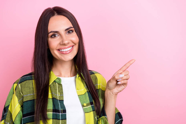 Portrait of positive person with long hairstyle wear yellow jacket indicating at discount empty space isolated on pink color background. - Фото, изображение