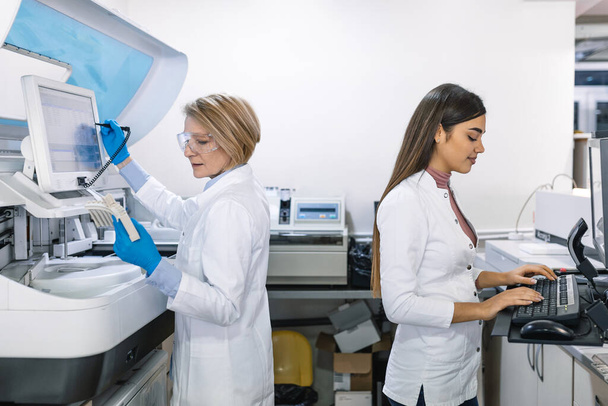 Team of Research Scientists Working On Computer, with Medical Equipment, Analyzing Blood and Genetic Material Samples with Special Machines in the Modern Laboratory. - Foto, afbeelding