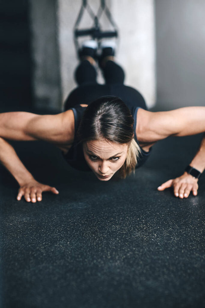No hay secreto, solo trabajo duro y determinación. una atractiva joven haciendo flexiones en un gimnasio - Foto, imagen