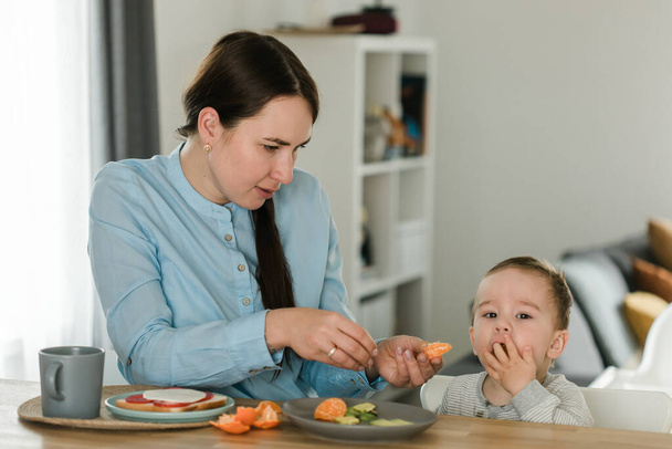 junge Mutter füttert ihren kleinen Sohn mit Fruchtpüree - Foto, Bild