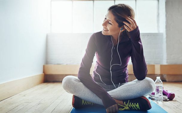 To poczucie spełnienia, które przychodzi po wielkim treningu. atrakcyjna młoda kobieta słuchająca muzyki podczas treningu w domu - Zdjęcie, obraz