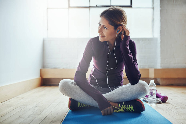 La música me ayuda a sentir la energía. una atractiva joven escuchando música mientras hace ejercicio en casa - Foto, Imagen