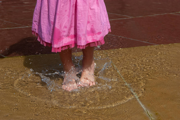 Splash von einem kleinen Mädchen im rosa Rock auf dem Wasser. - Foto, Bild