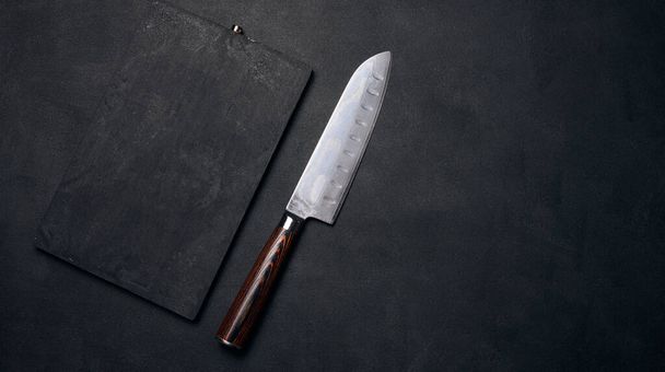 Empty black wooden cutting board and kitchen knife on black stoel, top view - Photo, Image