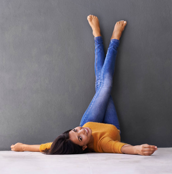 Mastering the art of relaxation. an attractive young woman lying on the floor with her feet against the wall - Zdjęcie, obraz