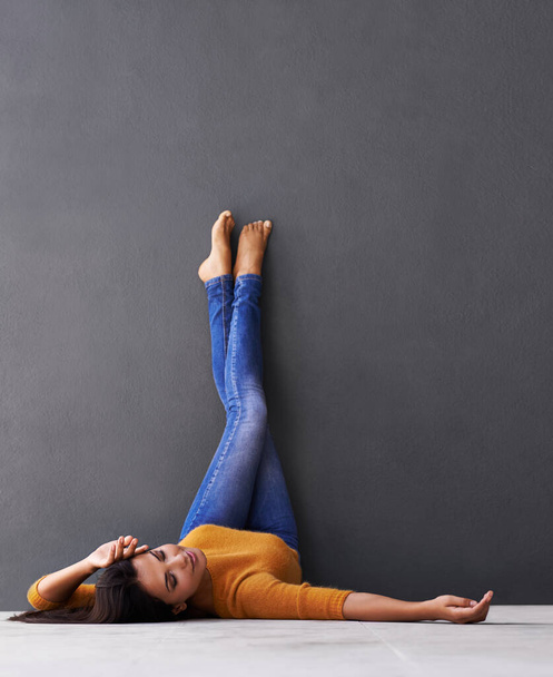 Просто уплывает... привлекательная молодая женщина, лежащая на полу, прислонившись ногами к стене - Фото, изображение