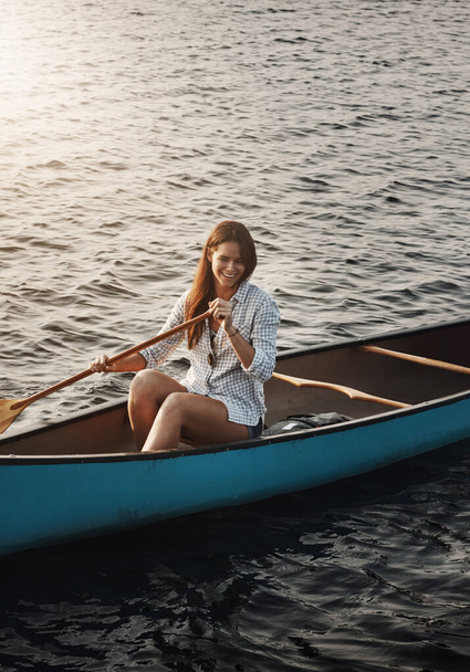 Πήγαινε στη λίμνη και ζήσε περιπέτειες. Μια όμορφη νεαρή γυναίκα κωπηλατεί μια βάρκα στη λίμνη. - Φωτογραφία, εικόνα