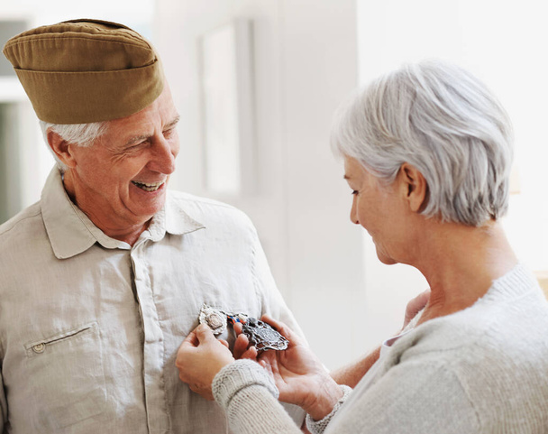 Military veteran, man and woman with medal, uniform and smile together with memory, pride and success. Elderly couple, army badge or regalia with happiness, check and retirement from service in house. - Foto, imagen