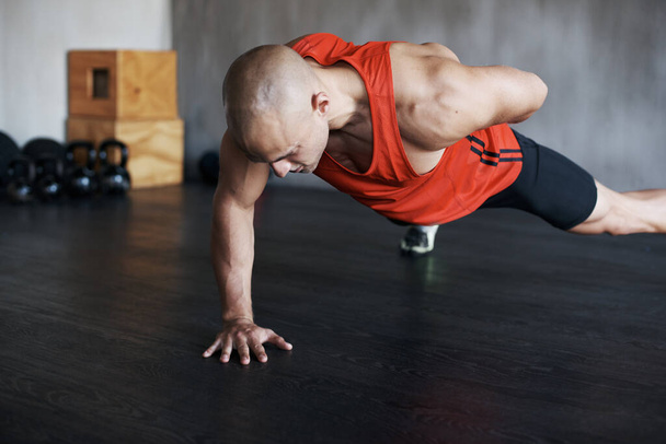 Training, muscle endurance and strong man doing push up for healthy lifestyle, strength development or health club commitment. One arm pushup, motivation and male athlete workout, fitness or exercise. - Photo, Image