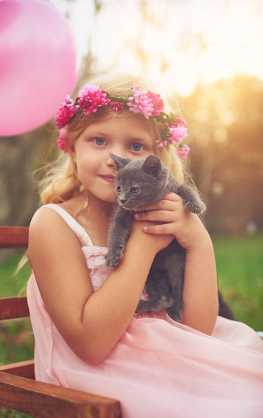 My little furball. a happy little girl holding a kitten and looking at the camera outside in the nature - Photo, Image