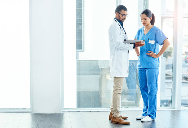 Zusammenarbeit mit Ihrer Sorgfalt im Hinterkopf. zwei junge Ärzte mit einem digitalen Tablet in einem modernen Krankenhaus - Foto, Bild