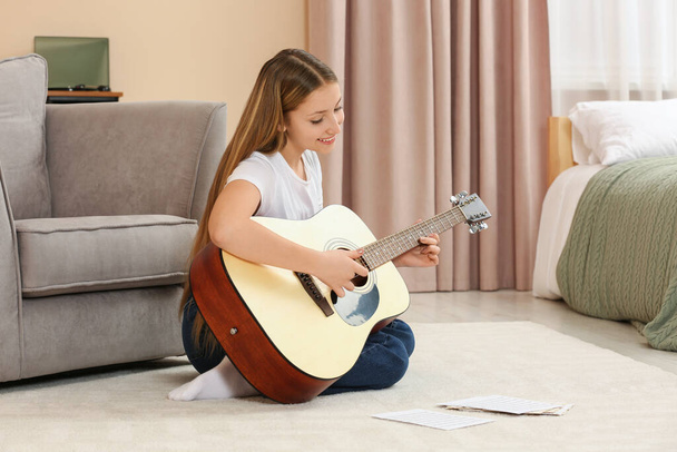 Teenage girl playing acoustic guitar in room - Fotó, kép