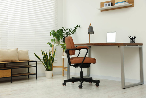 Stylish office interior with comfortable chair, desk, laptop and houseplants - Foto, Imagen