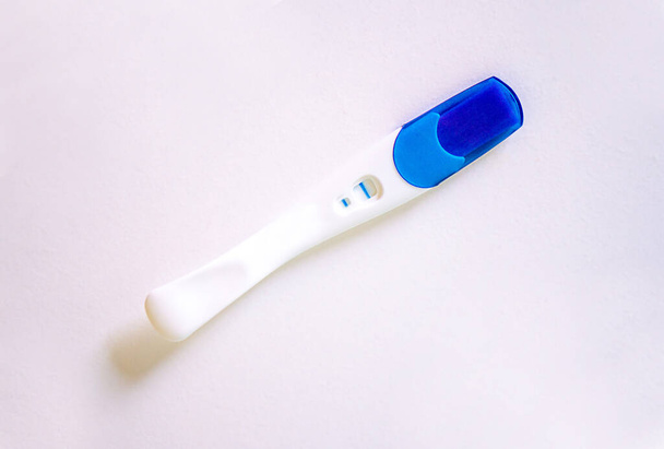 Θετικό τεστ εγκυμοσύνης με δύο ρίγες στο λευκό τραπέζι. Υψηλής ποιότητας φωτογραφία - Φωτογραφία, εικόνα