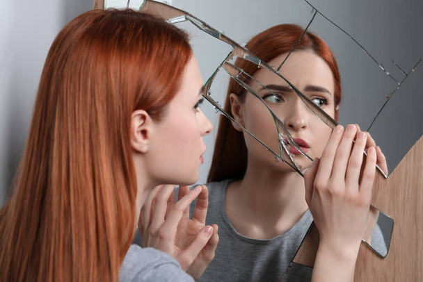 Sad young woman suffering from mental problems near broken mirror - Fotoğraf, Görsel