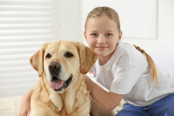Cute child with her Labrador Retriever at home. Adorable pet - Foto, afbeelding