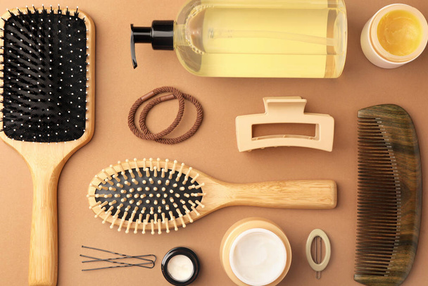 Flat lay composition with wooden hairbrushes and different cosmetic products on light brown background - Foto, immagini