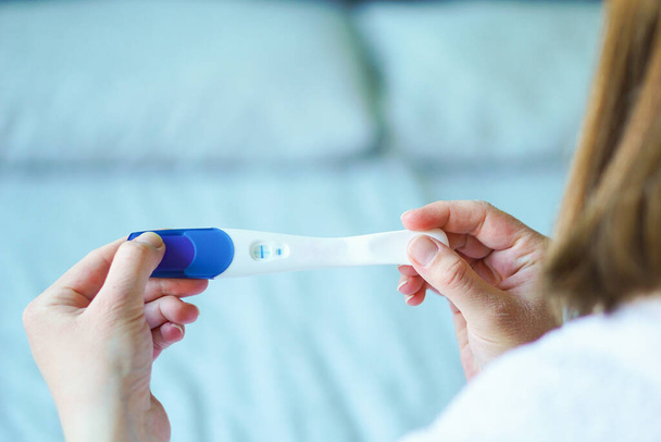 Women holding a baby pregnancy test with two stripes. Positive result. High quality photo - Zdjęcie, obraz