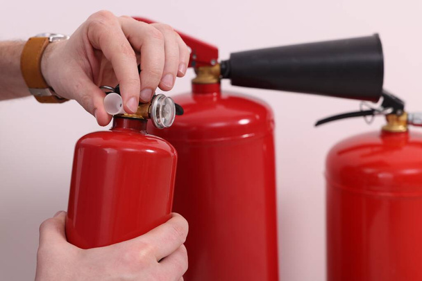 Man checking quality of fire extinguishers indoors, closeup - Foto, afbeelding