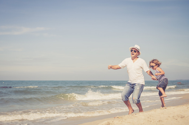 отец и сын играют на пляже в дневное время
. - Фото, изображение