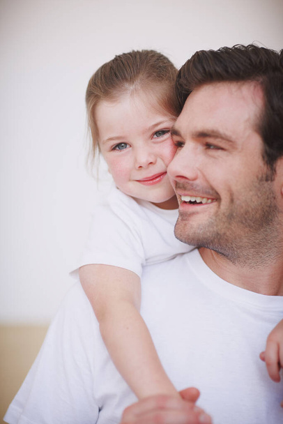 É dedicado à filha. Uma menina fofa amorosamente abraçando seu pai ao redor do pescoço - Foto, Imagem
