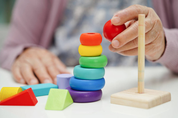 Asiatische ältere Frau spielt Puzzlespiel, um Gehirntraining für Demenz-Prävention, Alzheimer-Krankheit zu üben. - Foto, Bild