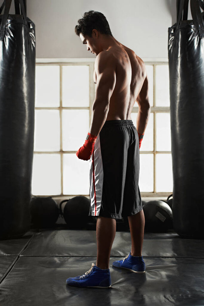 Zajmuje się sportem bokserskim. Full length shot przystojnego młodego boksera stojącego na siłowni - Zdjęcie, obraz
