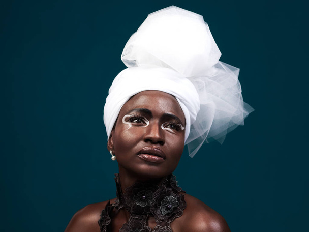 La haute couture rencontre le patrimoine. Plan studio d'une jolie jeune femme posant en tenue traditionnelle africaine sur fond bleu - Photo, image