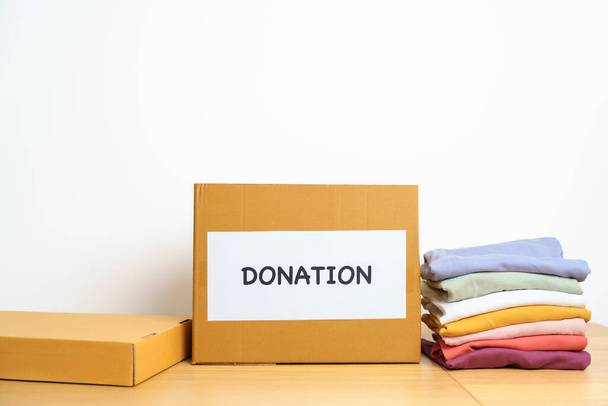 Donation, Charity, Volunteer, Giving and Delivery Concept. Clothes with Donation box at home or office for support and help poor, refugee and homeless people. Copy space for text - Photo, Image