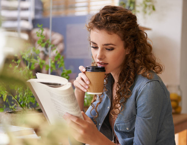 Relaks przy dobrej książce. Młoda kobieta czytająca książkę w kawiarni - Zdjęcie, obraz