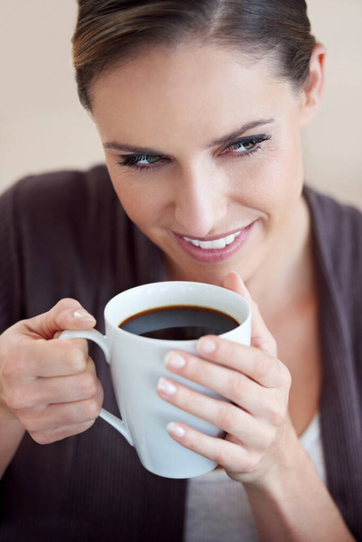 Coffee got her thinking. a beautiful woman looking thoughtful while holding her coffee - Foto, imagen