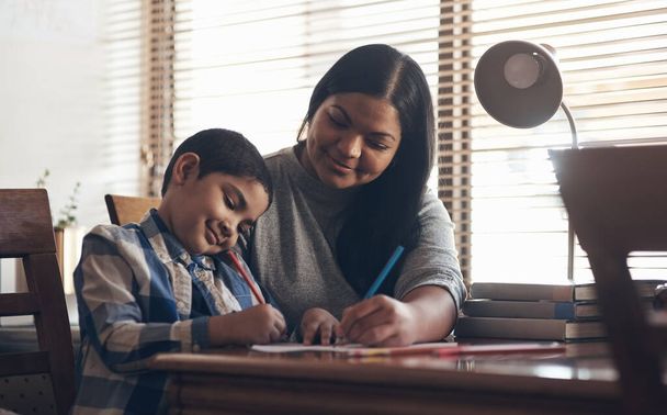 Gdziekolwiek jesteśmy, tam się ucz. uroczy chłopiec wykonujący zadanie szkolne ze swoją matką w domu - Zdjęcie, obraz