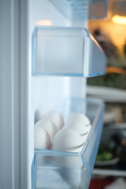  white eggs on the refrigerator shel - Фото, изображение