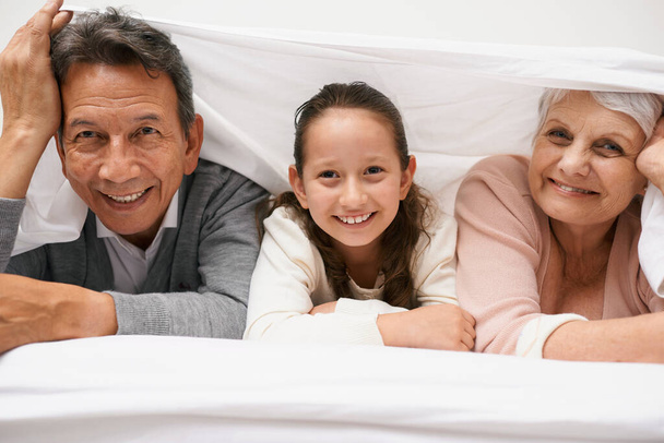 Portrait, grandparents or happy child in bedroom to relax together for bonding in Australia with love or care. Morning, faces or grandmother with fun girl or old man to enjoy quality time on bed. - Foto, imagen