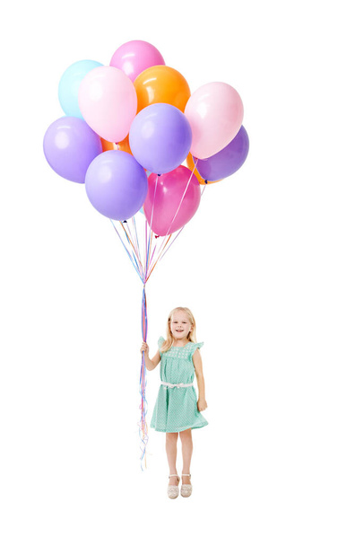 Up, up and away. Studio shot of a cute little girl holding a bunch of balloons in mid-air against a white background - Zdjęcie, obraz