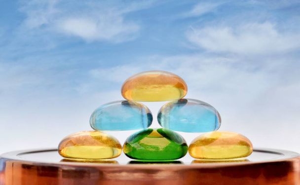 Stack of colored glass stones with a blue sky background and copy space. Zen concept of life balance, tranquility, feng shui and related topics. - Photo, Image