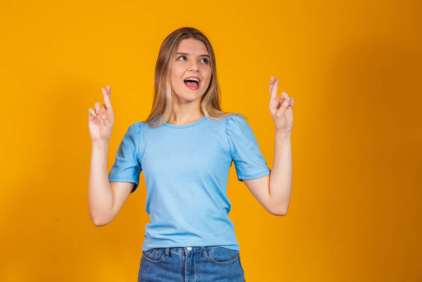 Image of a happy positive young girl isolated over yellow wall background make hopeful please gesture. Pretty girl with her fingers crossing over yellow background. - Zdjęcie, obraz