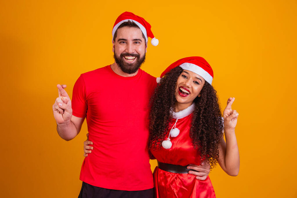 Young valentine couple dressed for Christmas night on yellow background with space for text. - 写真・画像