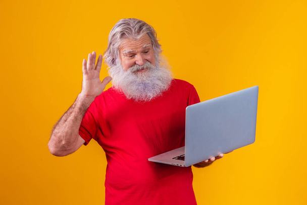 old man on yellow background making a video call on the laptop. - Фото, зображення