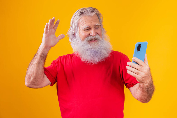 Cheerful elderly man holding a smartphone, having video call online, chatting with grown children, communicating with a friend at a distance, older generation modern technology comfortable user-friendly concept. - Photo, image