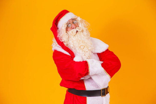 Santa Claus with crossed arms on yellow background. - Foto, Imagen